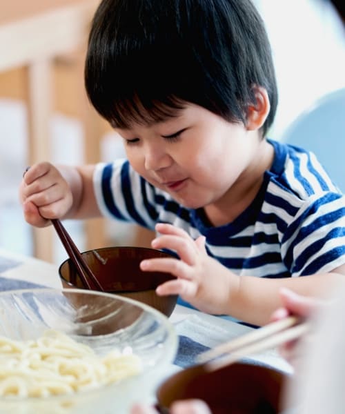 小さい子供がめんをほおばる様子